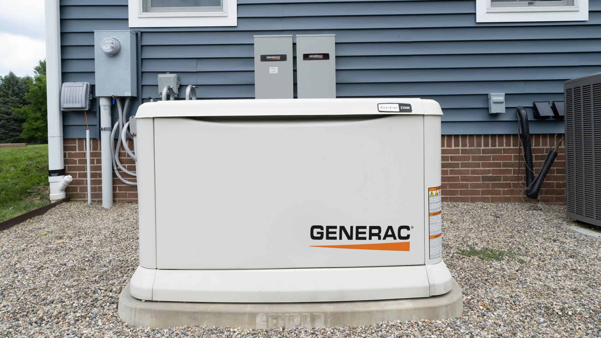 generac-generator-professionally-installed-and-serviced-sitting-on-a-concrete-pad-on-the-side-of-a-residential-home-with-a-transfer-switch-in-the-background