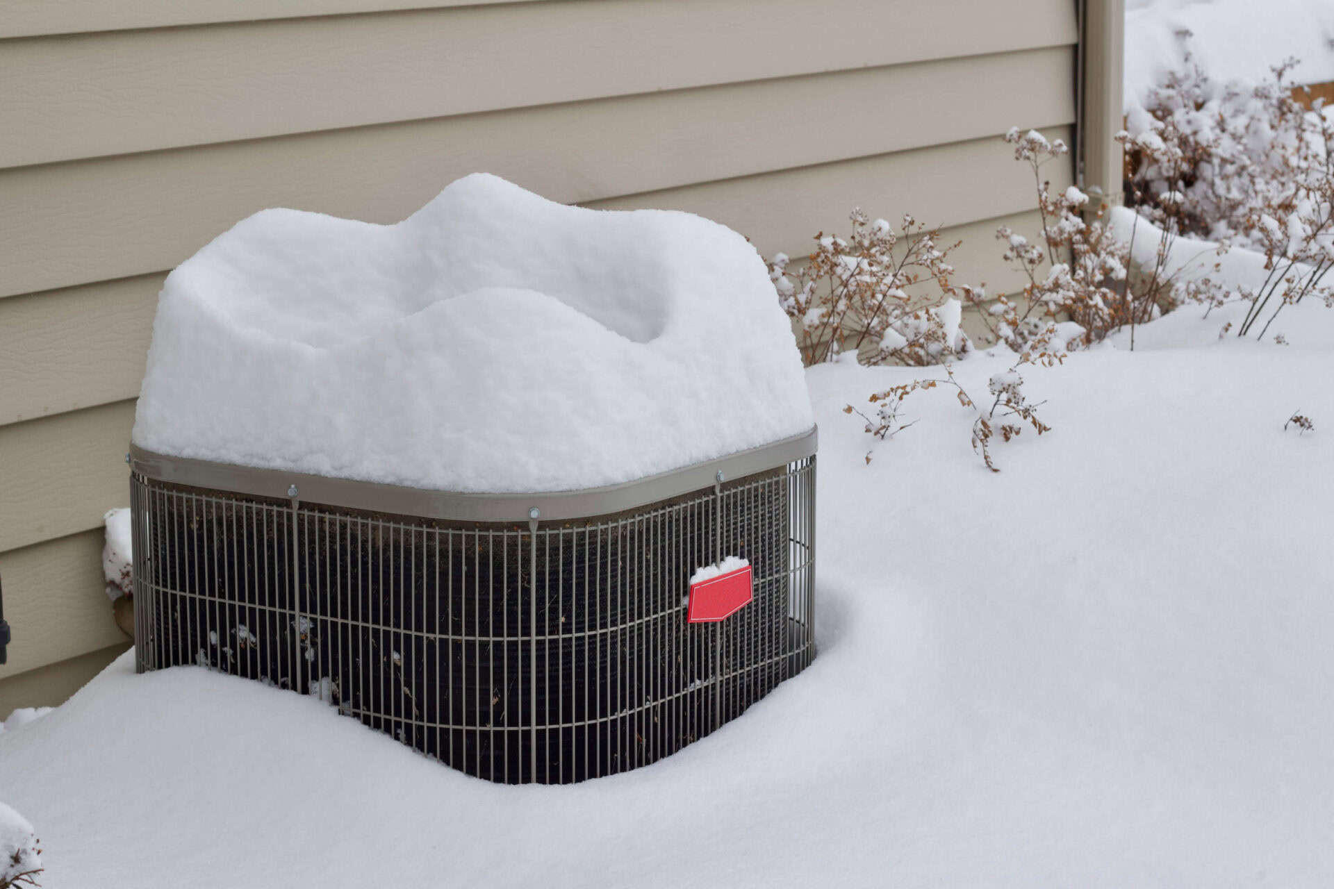 outdoor home air conditioner unit covered with deep snow in winter